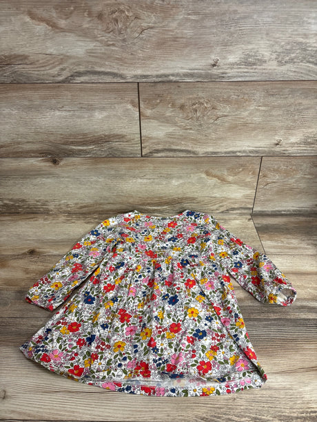 Flat lay of girls' long-sleeve floral dress (4T) showcasing gathered waist and long sleeves with elastic cuffs on a wood plank background