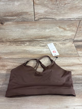 Flat lay of Supportive Flow nursing and pumping sports bra in espresso, size M, V-neck front, crisscross back straps, wide underband on wood