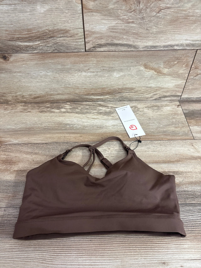 Flat lay of Supportive Flow nursing and pumping sports bra in espresso, size M, V-neck front, crisscross back straps, wide underband on wood