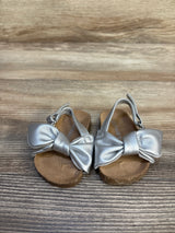 Silver toddler sandals with bows on wooden surface, kids shoes, gently used footwear