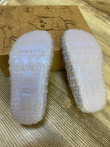 Soles-up view of Mini Melissa Campana Papel jelly flats showing textured translucent soles on wood floor with illustrated shoe box