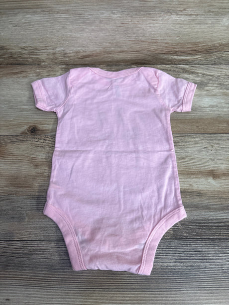 Light pink short-sleeve baby onesie laid flat on wooden floor, children's clothing