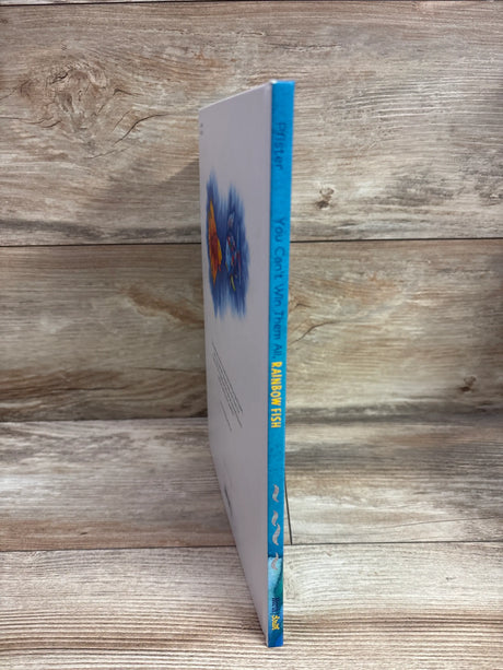 Side view of The Rainbow Fish hardcover book showcasing its blue spine with a wood-grain background