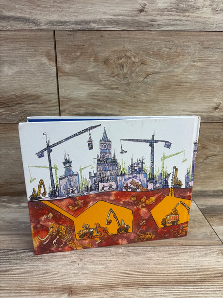Front view of Builders and Breakers hardcover book showing cranes, excavators, and underground fossils on a wood floor