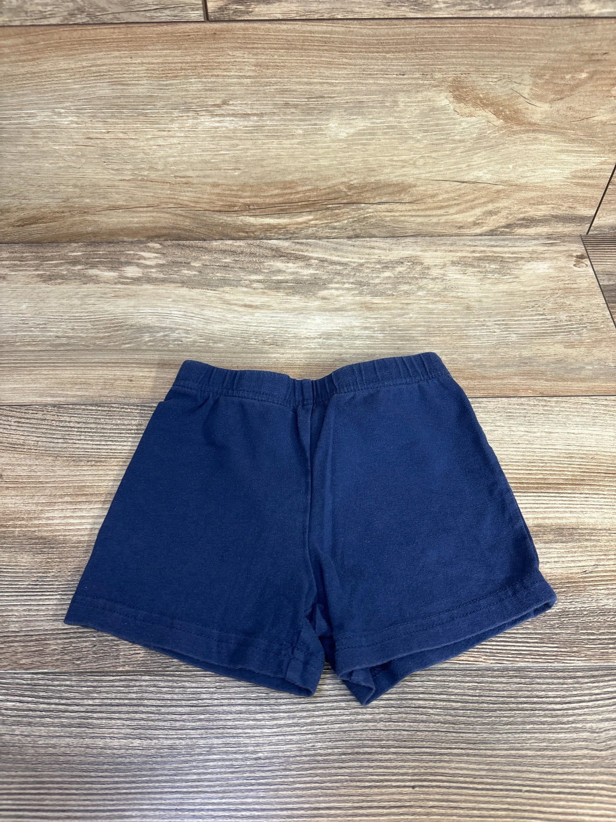 Front view of navy Carter's toddler bike shorts showing elastic waistband and hemmed legs on wood background