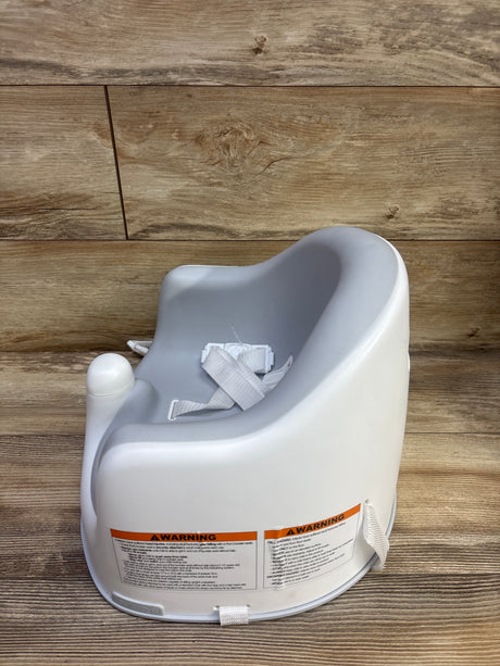 Rear three-quarter view of JoolBaby Booster Floor Seat showcasing its safety harness and securing straps on a wood floor