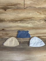 Top view of three Gerber newborn knit hats showing a blue hat with ears and two striped hats on wood background