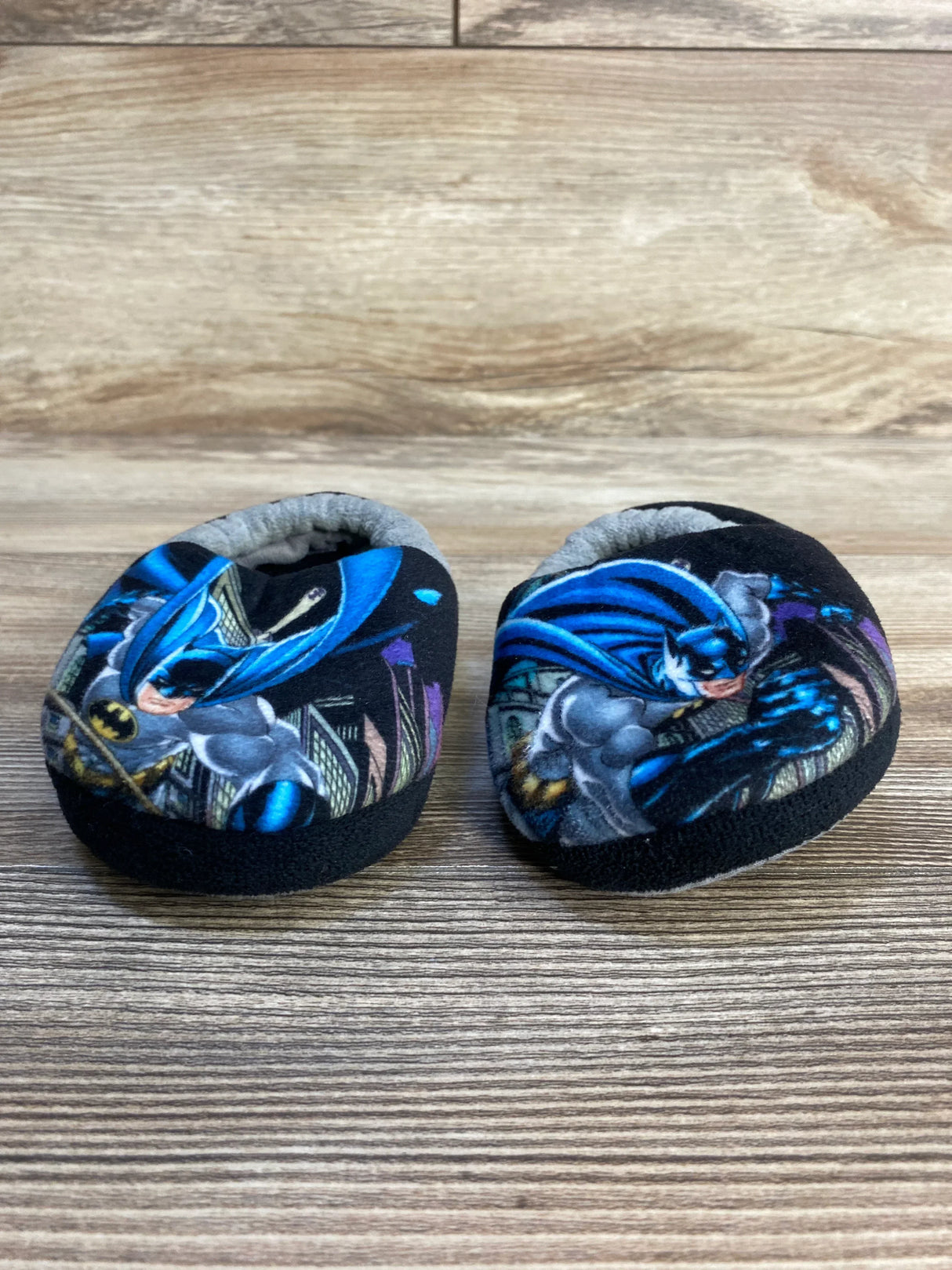 Batman themed baby booties on wood background