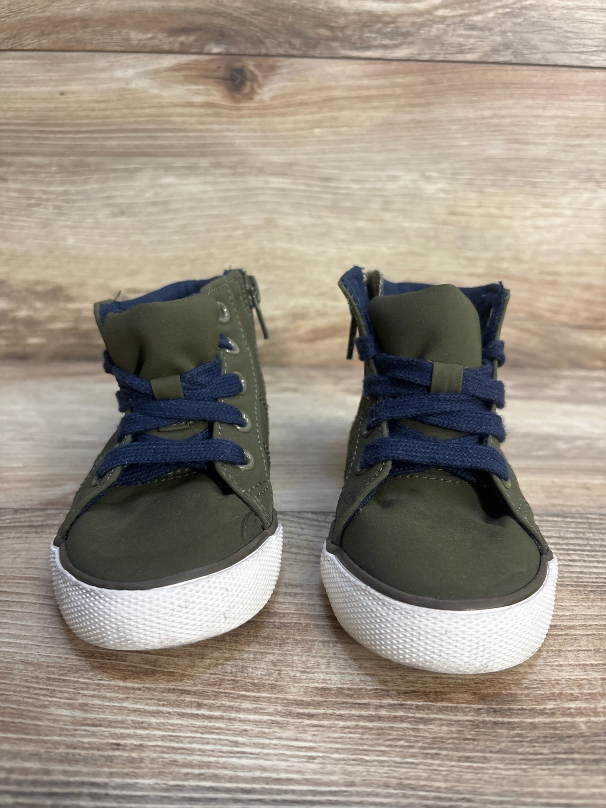 Pair of olive green toddler sneakers with navy blue laces on wood background