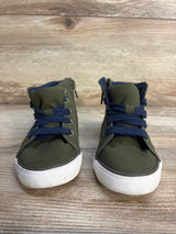 Pair of olive green toddler sneakers with navy blue laces on wood background