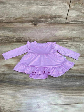 Flat lay of purple tiered ruffle baby dress showing long sleeves, ruffle shoulders and double ruffle hem on wood background