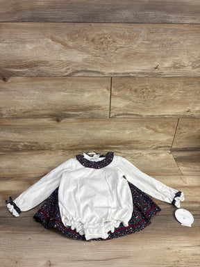 Long sleeve white baby romper with floral ruffle trim and matching skirt on wood background