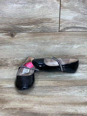Front and side view of girls' black faux patent leather ballet flats with jeweled cross strap on wood plank floor