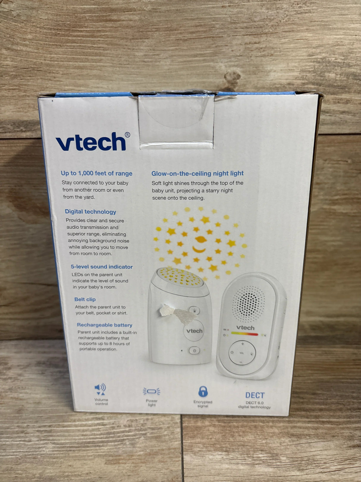 Front view of VTech TM8112 baby monitor box showing projector star graphic and parent and baby unit images on wood background