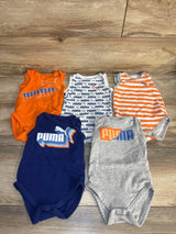 Assorted Puma baby bodysuits in orange, blue, and gray on wooden floor