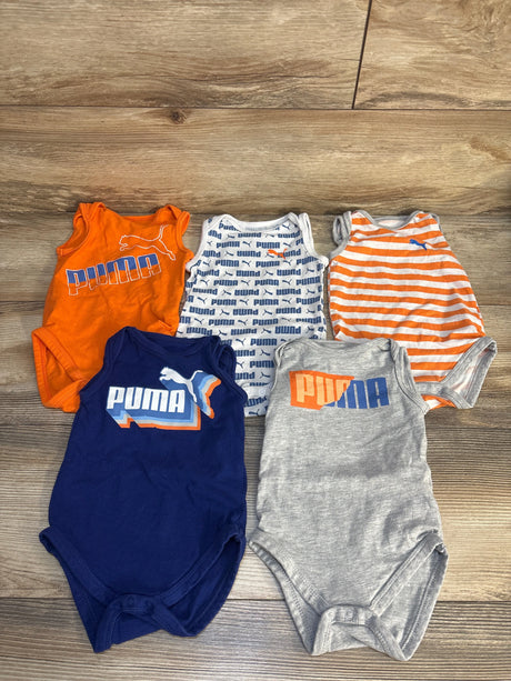 Assorted Puma baby bodysuits in orange, blue, and gray on wooden floor