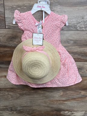 Pink eyelet baby dress with matching straw sun hat, displayed on wooden background.