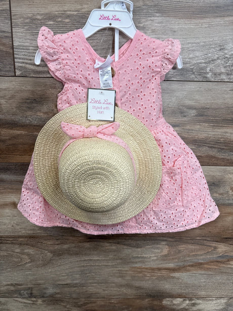 Pink eyelet baby dress with matching straw sun hat, displayed on wooden background.