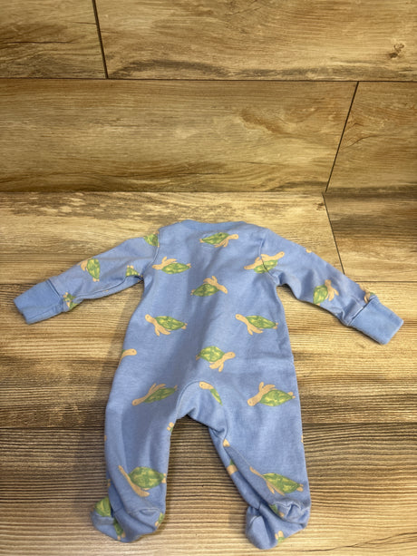 Top view of Child Of Mine blue sleeper showcasing long sleeves, footed legs, and all-over turtle print on a wood floor
