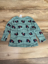 Green long sleeve toddler shirt with colorful truck print, laid flat on wood background
