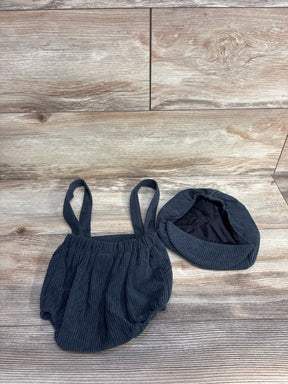 Dark blue corduroy baby romper with straps and matching hat on wooden floor