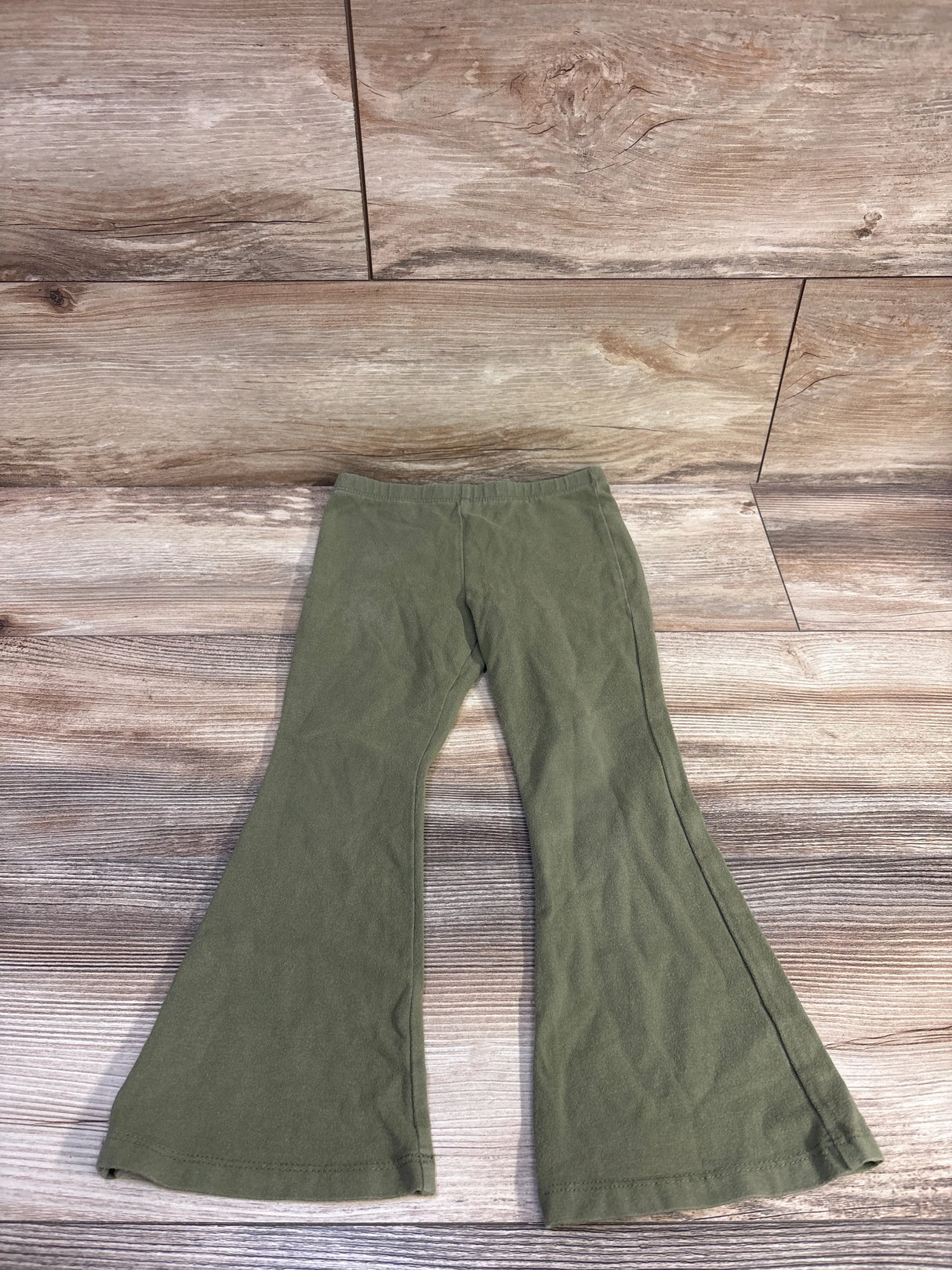 Flat lay of Cat and Jack green toddler flare leggings size 4T with elastic waist and flared legs on light wood background