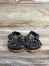 Front view of Childrens Place leather fisherman sandals in dark brown with white contrast stitching on wood plank floor
