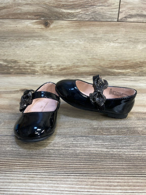 Black patent leather toddler girl dress shoes with beaded bow on wooden floor