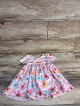 Flat lay of pink Mila and Rose twirl dress showcasing multicolored butterfly print and short puff sleeves on wood background