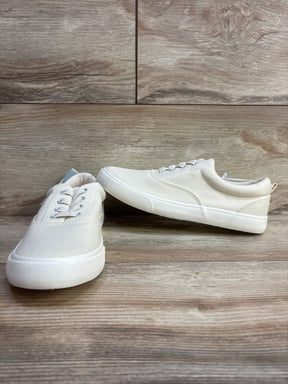 White canvas sneakers for kids with rubber soles on wood background