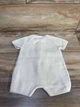 Back view of ivory knit shortie romper showcasing ribbed texture and short raglan sleeves on wood plank background