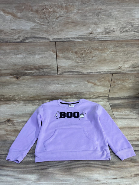 Front of Joyful Moments purple pullover sweatshirt with BOO chest print, ghost icon, and kangaroo pocket on wood background
