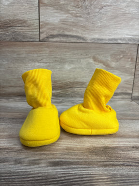 Pair of bright yellow baby booties with ribbed cuffs on wooden floor background