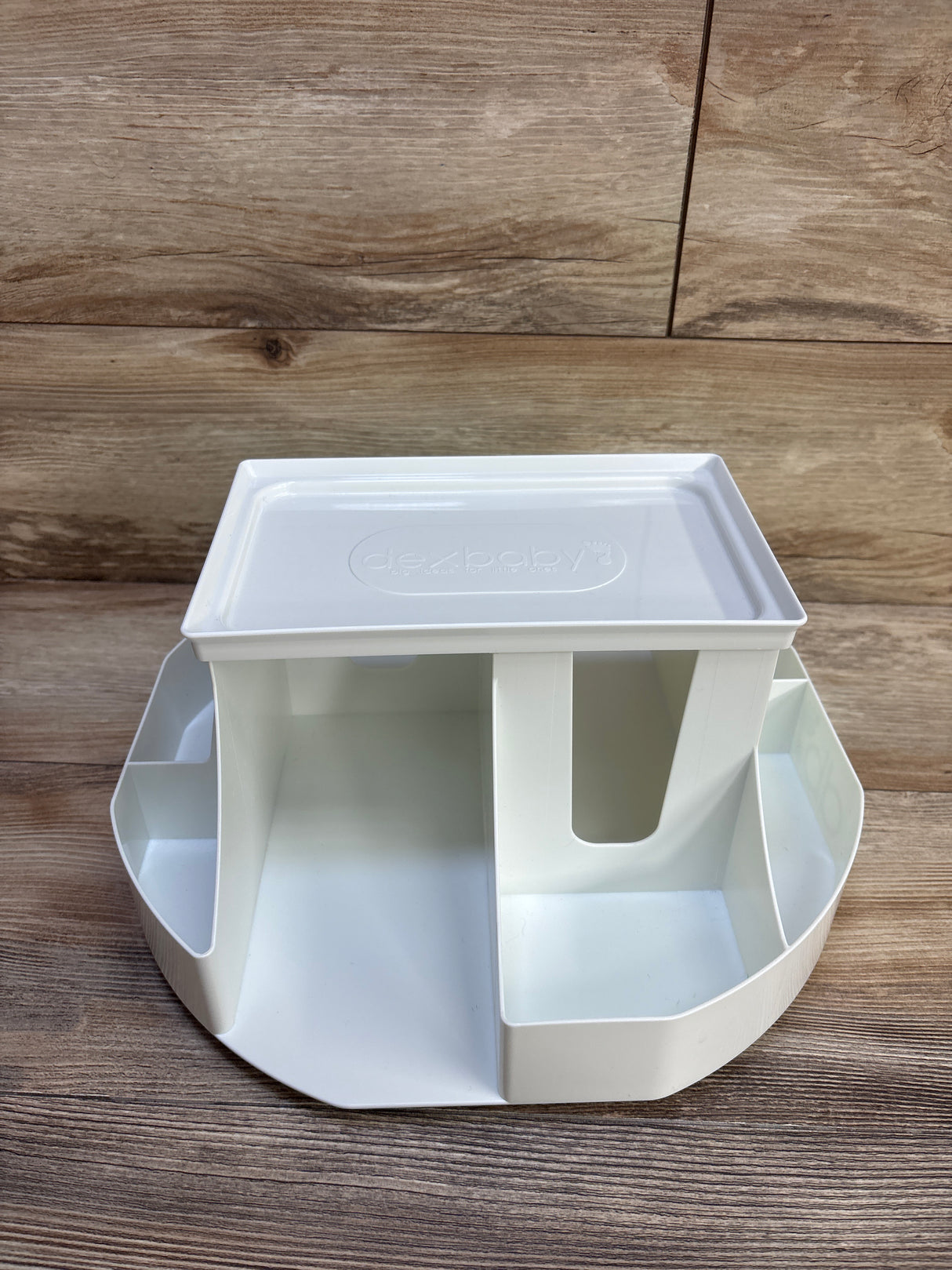 Front view of Dexbaby Spin changing station in white showing rotating base with four compartments and removable top tray on wood background