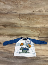Front view of Carter’s football shirt in white with navy sleeves, featuring an alligator football graphic on a wood floor