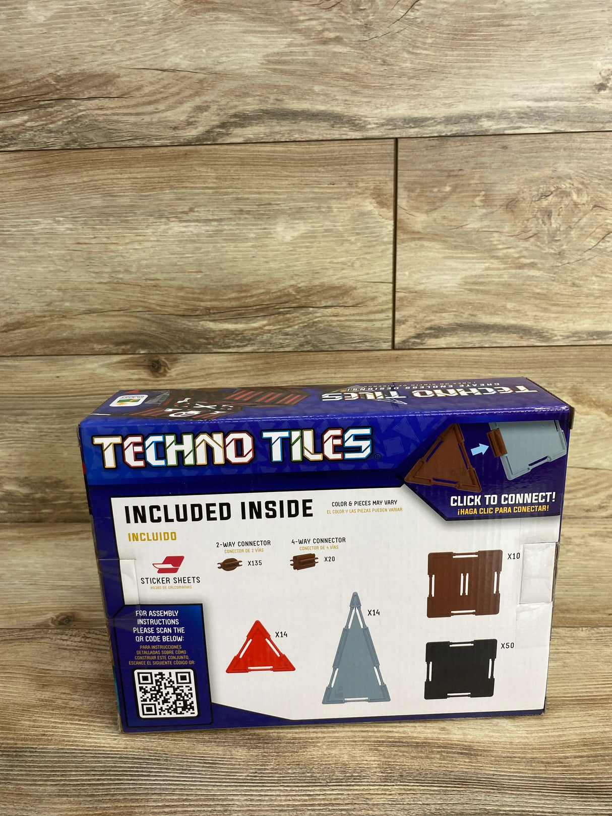 Techno Tiles building set box showing included connectors, triangle and square tile pieces on wood floor.