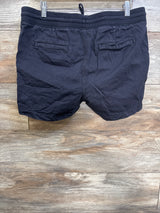 Back view of black Gap maternity shorts with ribbed elastic waistband, drawstring loop and back welt pockets on wood background