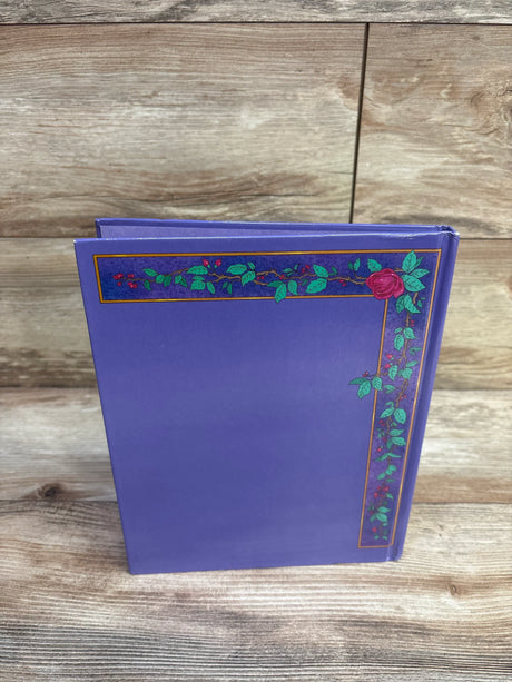 Upright Disney Beauty and the Beast hardcover book showing purple cover with rose vine border on a light wood surface