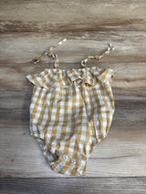 Yellow and white gingham baby romper with ruffled straps and snap closures on wood background