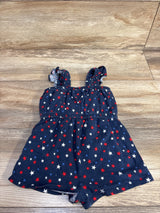 Flat-lay front of navy toddler sleeveless romper (size 12-18 months) showcasing red, white, and blue star print, ruffle shoulder straps, and elasticized bodice on a light wood floor