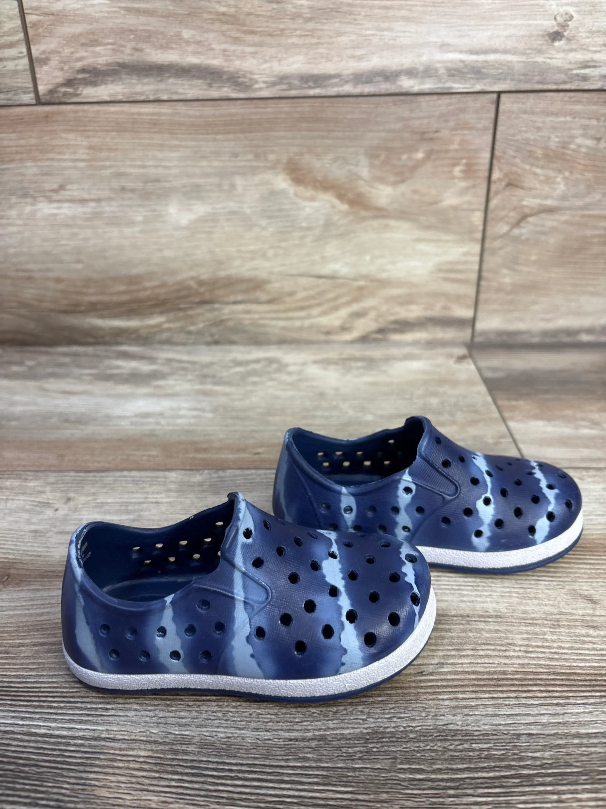 Front three-quarter view of Cat and Jack Jese toddler slip-on water shoes in blue showing perforated upper and white sole on wood floor background