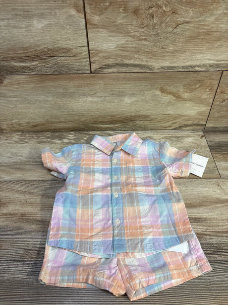 Flat lay of coral plaid shirt and matching shorts showcasing pastel plaid and front buttons on wood background