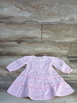 Flat lay of pink Old Navy long-sleeve tiered dress showcasing double-weave fabric and ruffled tiers on light wood floor