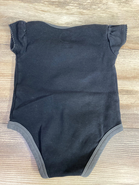 Black baby onesie with short sleeves and grey trim on wooden floor