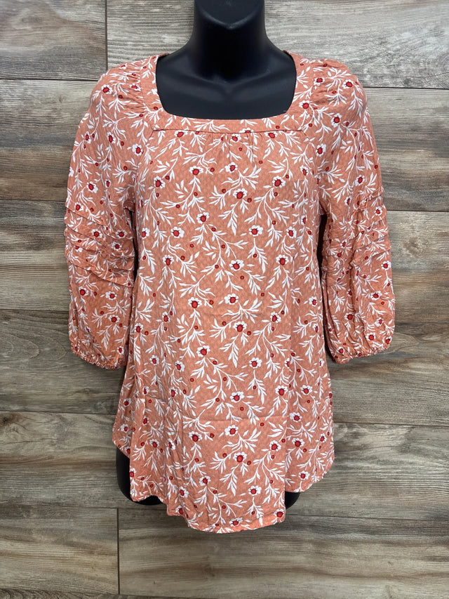 Front view of orange maternity floral blouse showing square neckline, ruched three-quarter sleeves and white-red floral print on wood background