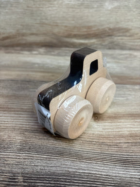 Three-quarter view of Maple Landmark Mini Monster Pickup wooden car showing black-painted cab, natural maple body, round wheels, plastic wrap on wood-grain surface