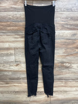 Back view of maternity full-panel distressed black jeans showing elastic belly panel, frayed hems and pockets on wood floor