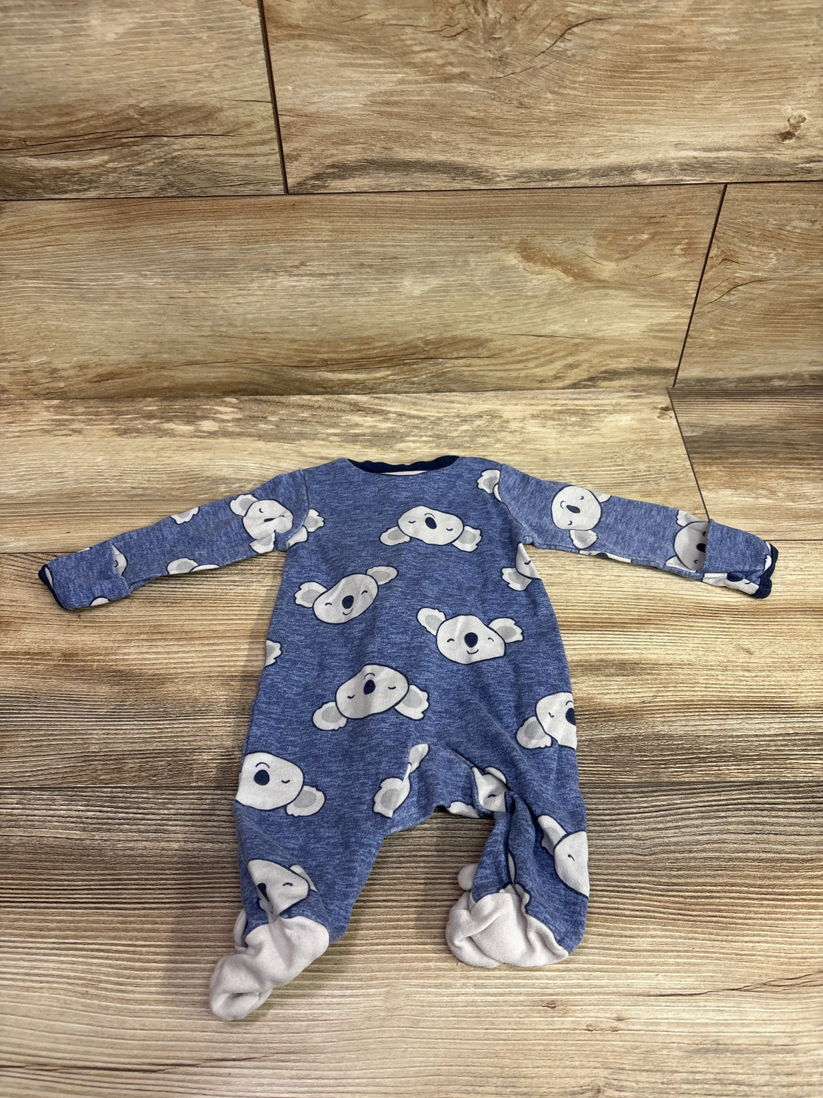 Blue Carter's newborn sleeper with white koala print on a wooden background