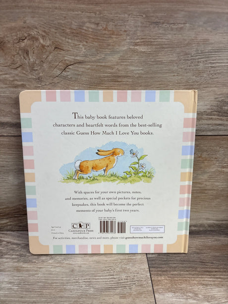 Back cover of Guess How Much I Love You baby book showcasing a rabbit illustration and pastel border on a wood surface
