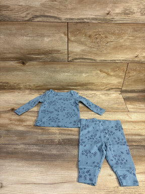 Top-down view of a blue two-piece waffle knit shirt and pants set with floral pattern, laid flat on a wood-grain background